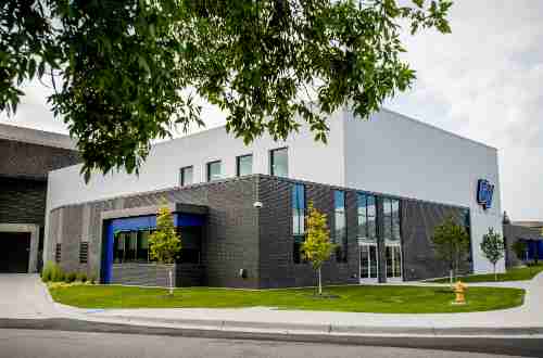 A full view of the new wrestling complex. It is connected to the fieldhouse and is white and brick with bright blue accents. 